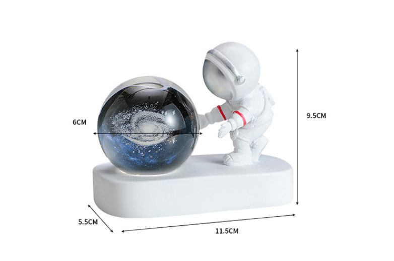 Astronaut figurine pushing a galaxy ball with measurements on a white background