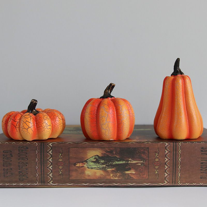 Three decorative pumpkins on a vintage book with a plain background