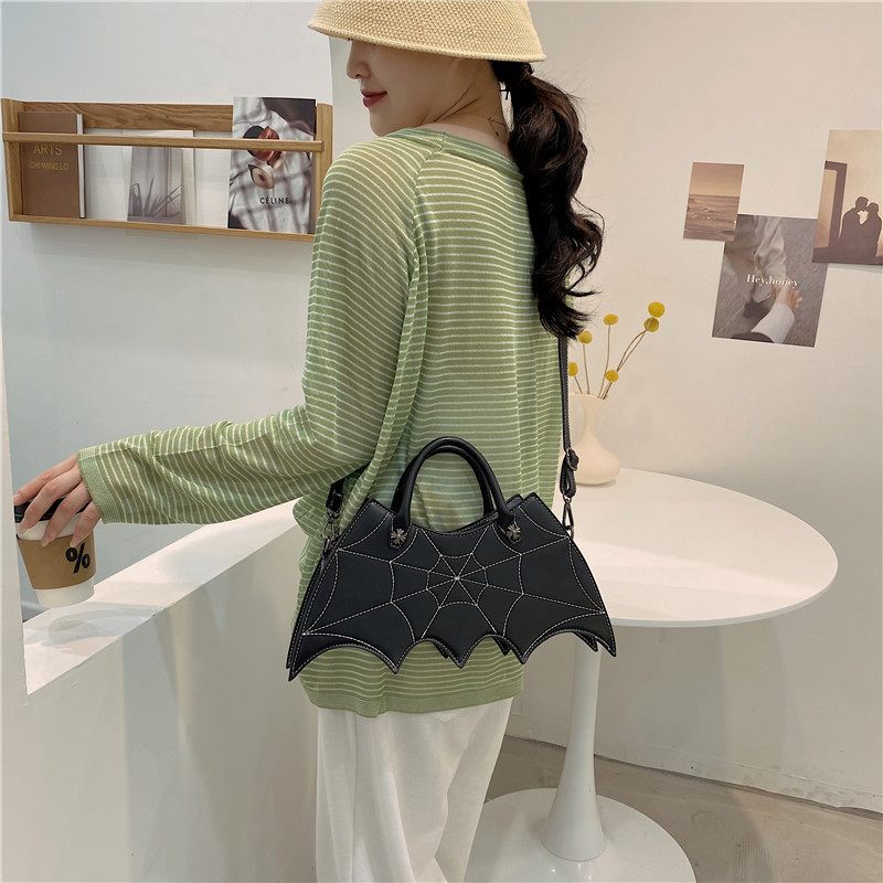 Woman holding a black bat-shaped handbag in an indoor setting
