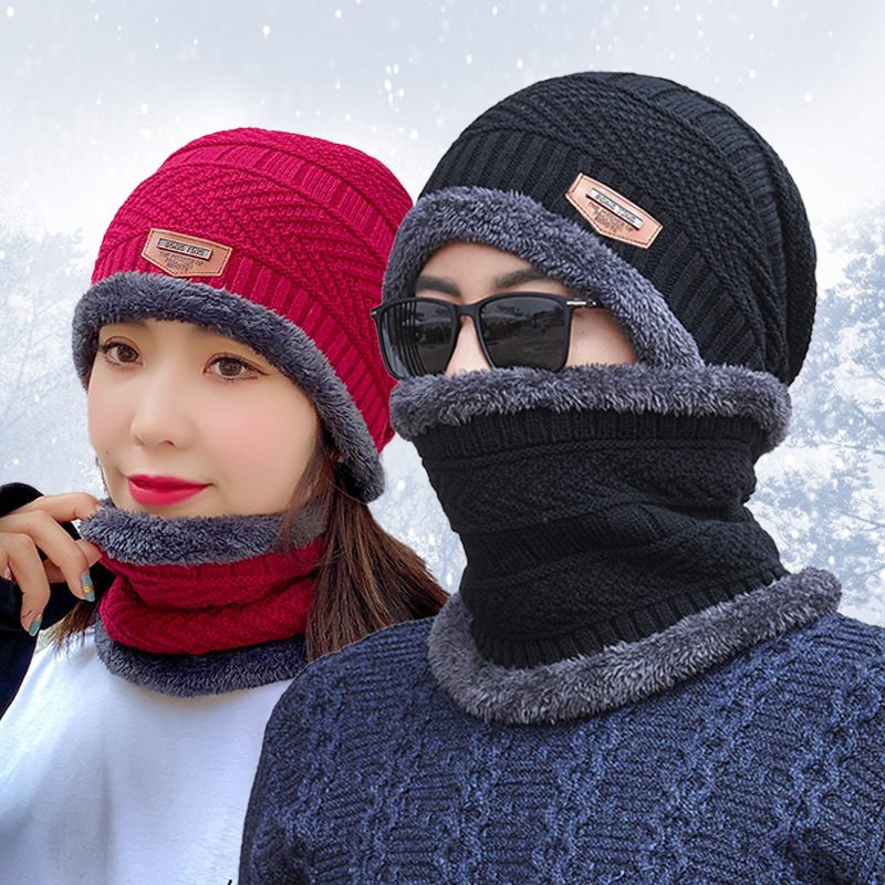 Two people wearing knitted hats and scarves with a snowy background