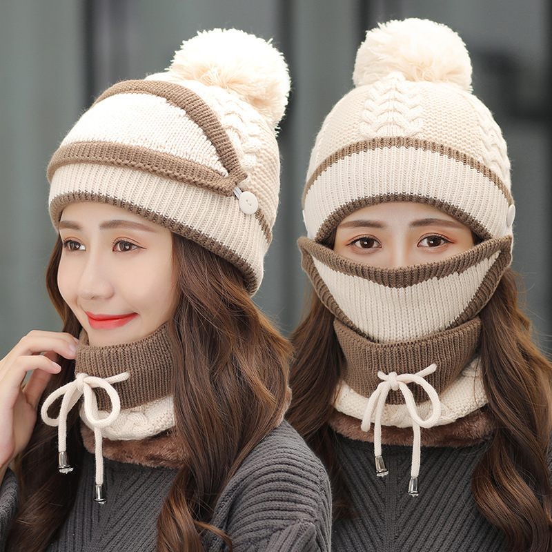 Two women wearing matching knit hats and scarves with pom-poms on a neutral background.