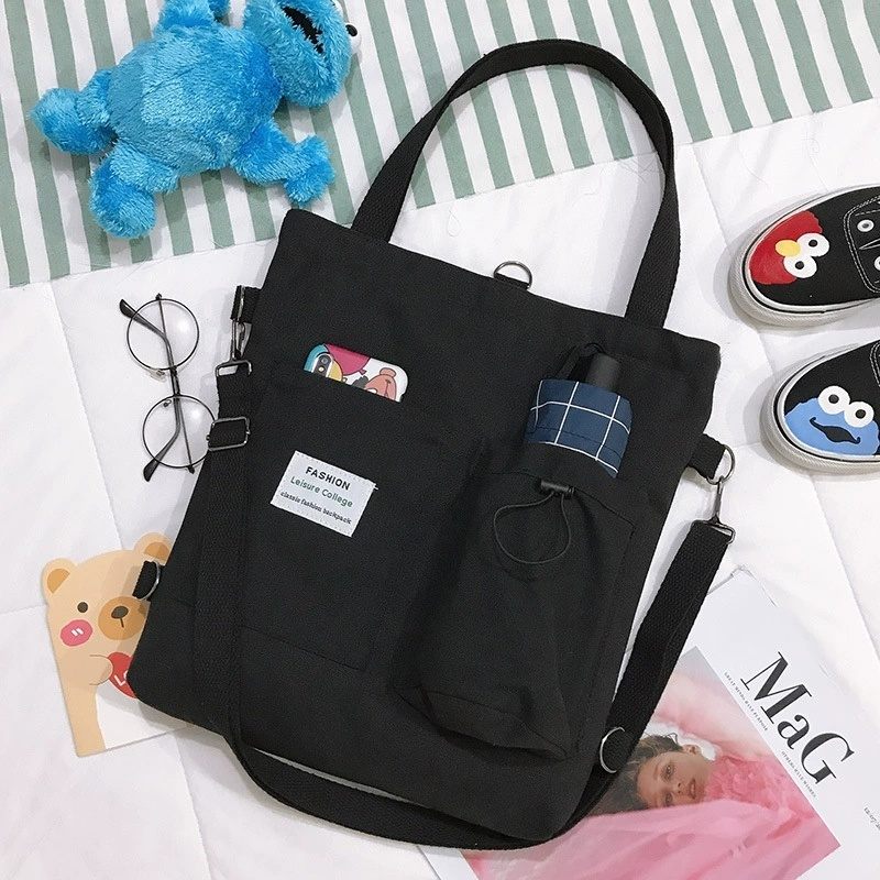 Black tote bag with a label on a surface with various items around