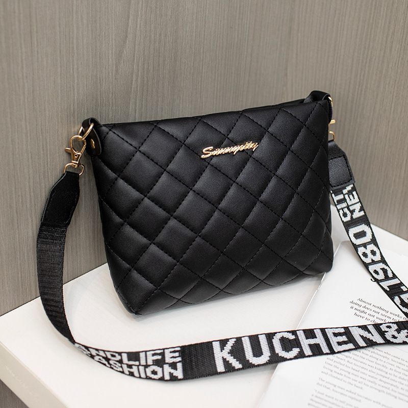 Black quilted handbag with a strap on a wooden surface