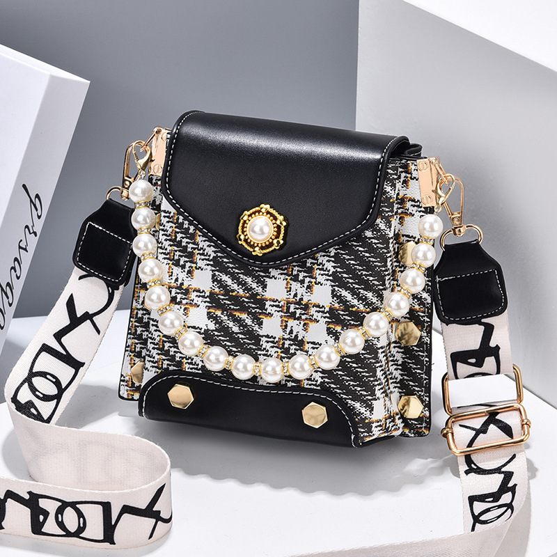 Black handbag with pearl embellishments on a white surface