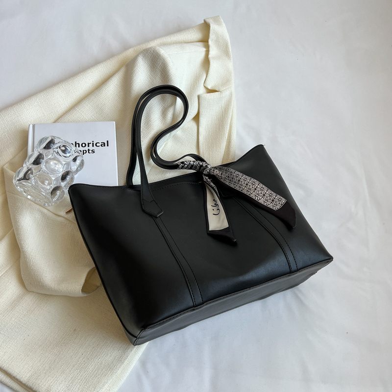 Black handbag with a decorative bow on a white surface