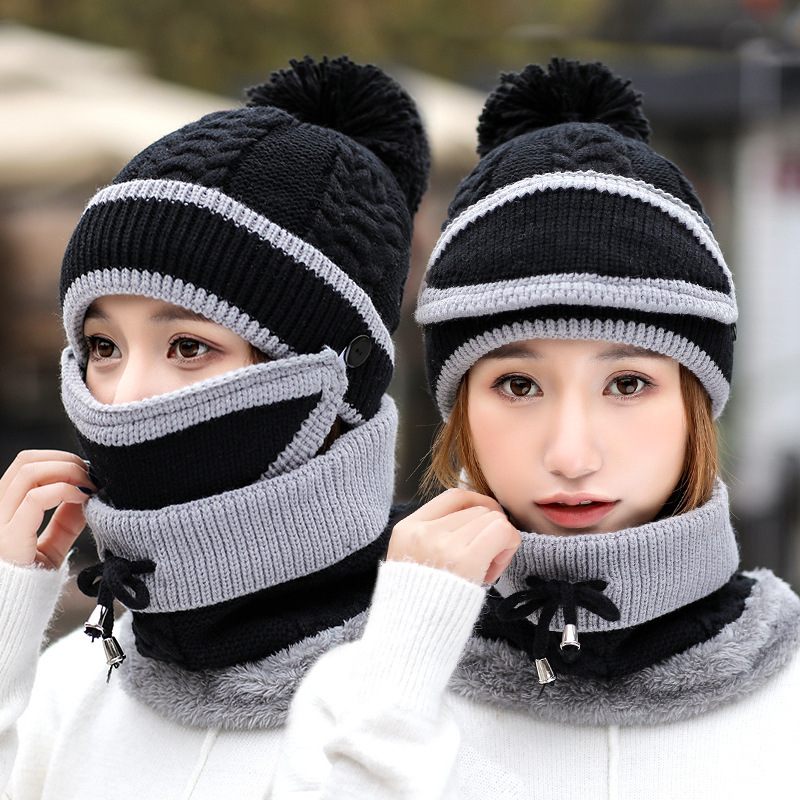 Two people wearing black and gray knitted hats and scarves with pom-poms.