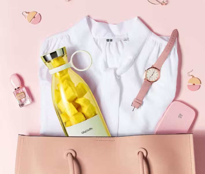 White shirt with yellow water bottle, pink watch, and pink handbag on a pink background