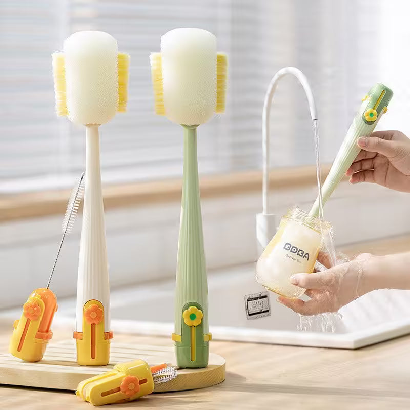Two kitchen cleaning brushes withstands and a hand holding one, on a light wooden surface.