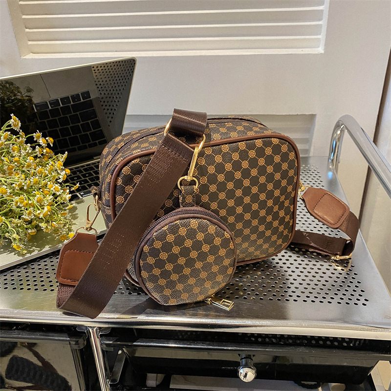 Brown checkered handbag with a matching round pouch on a metallic surface.