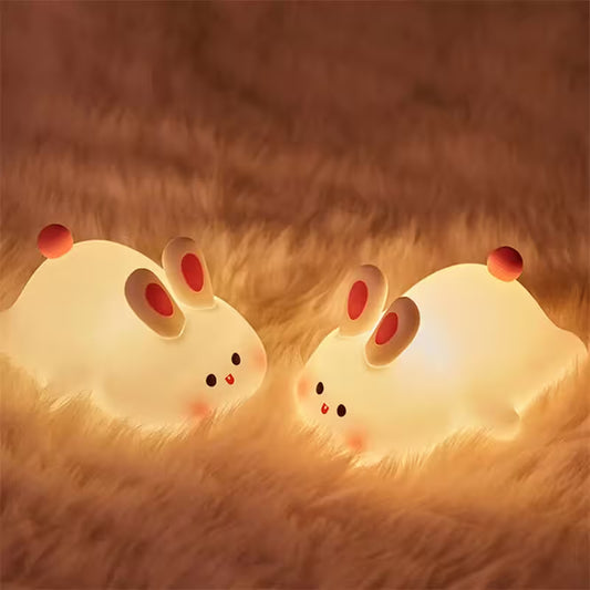 Two glowing rabbit-shaped night lights on a textured brown surface