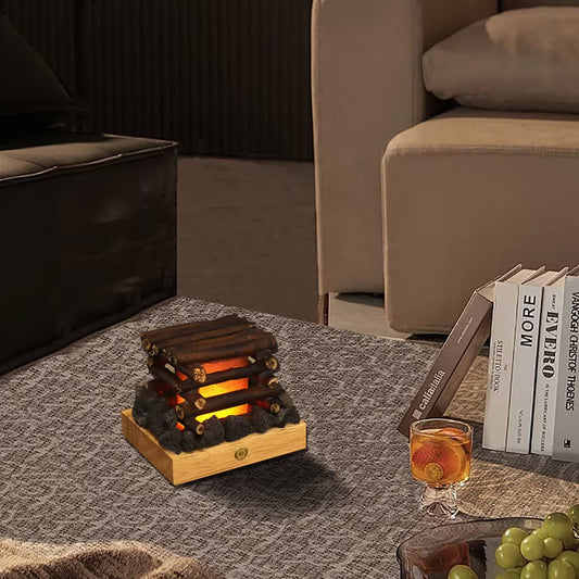 Small fire pit on a coffee table with books and a glass of wine in a cozy living room setting.