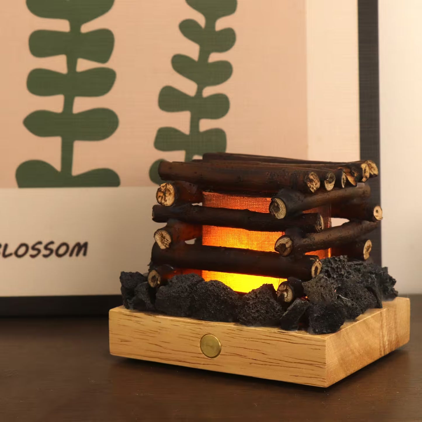 Wooden log-style lamp with glowing interior on a wooden base, against a decorative wall.
