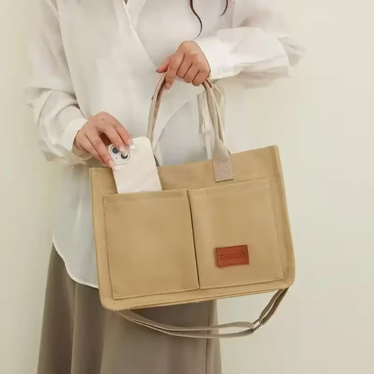 Beige tote bag held by a person against a plain background
