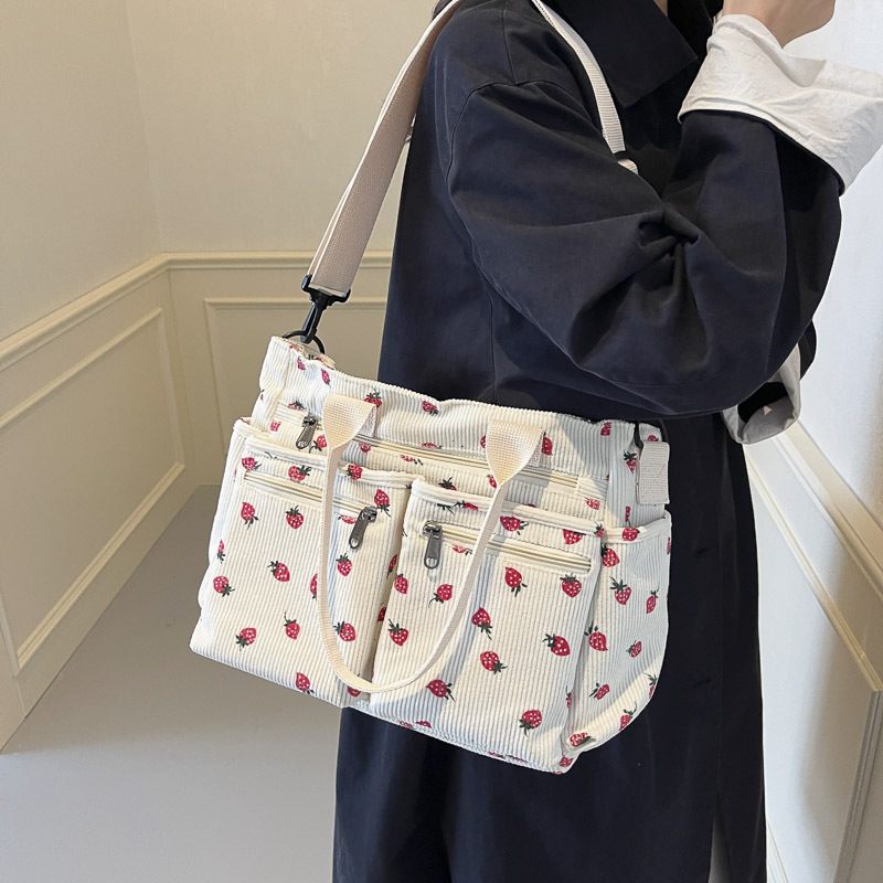 Person holding a white handbag with red floral pattern