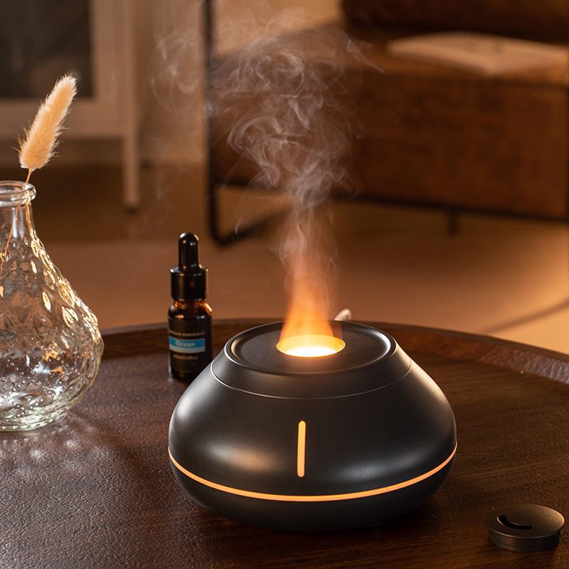 Aromatherapy diffuser with steam, bottle, and vase on a wooden surface.