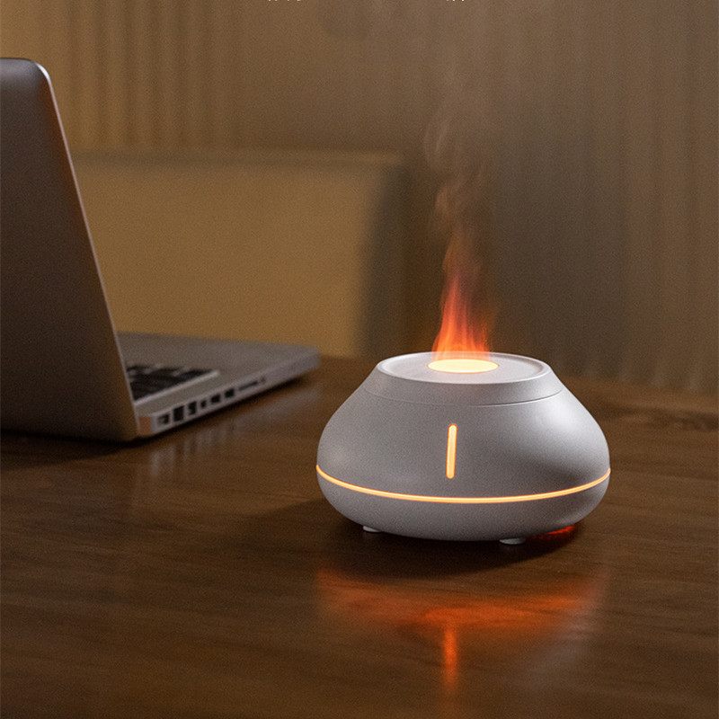 Small flameless candle on a wooden surface next to a laptop