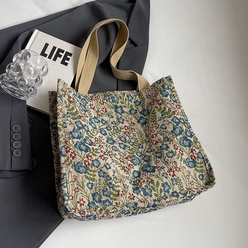 Floral-patterned tote bag on a white surface with a book and glassware in the background.
