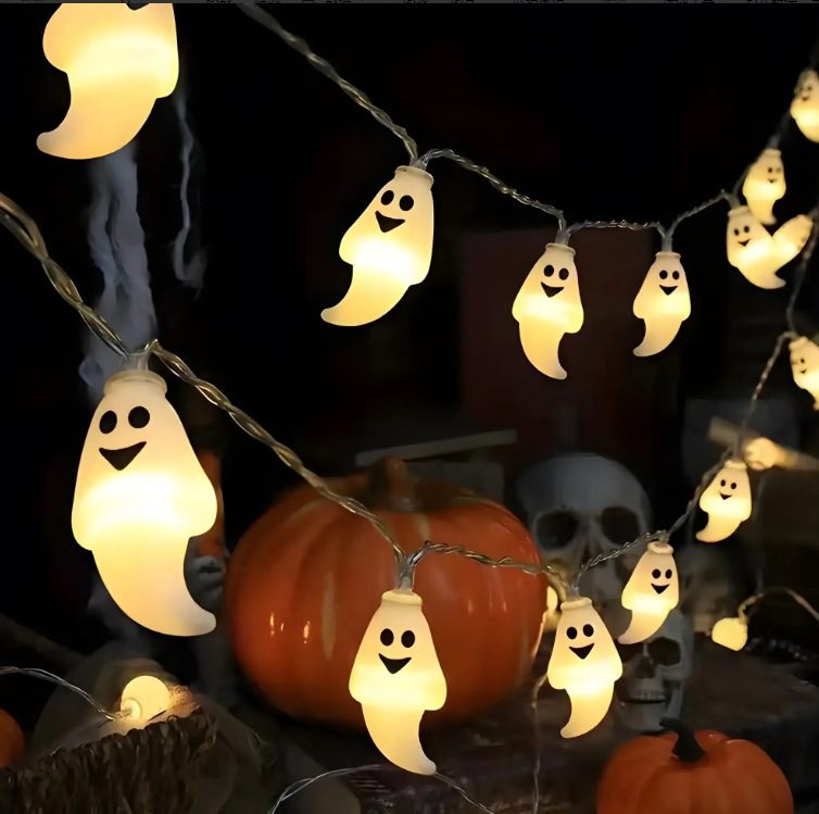 String of ghost-shaped lights with pumpkins and a skull on a dark background