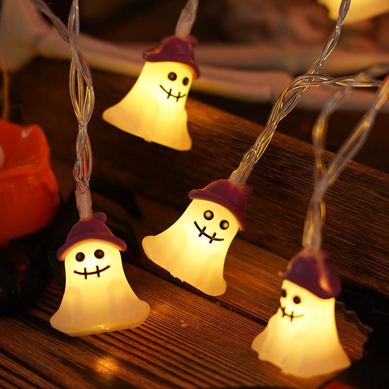String lights shaped like ghosts with purple hats on a wooden surface