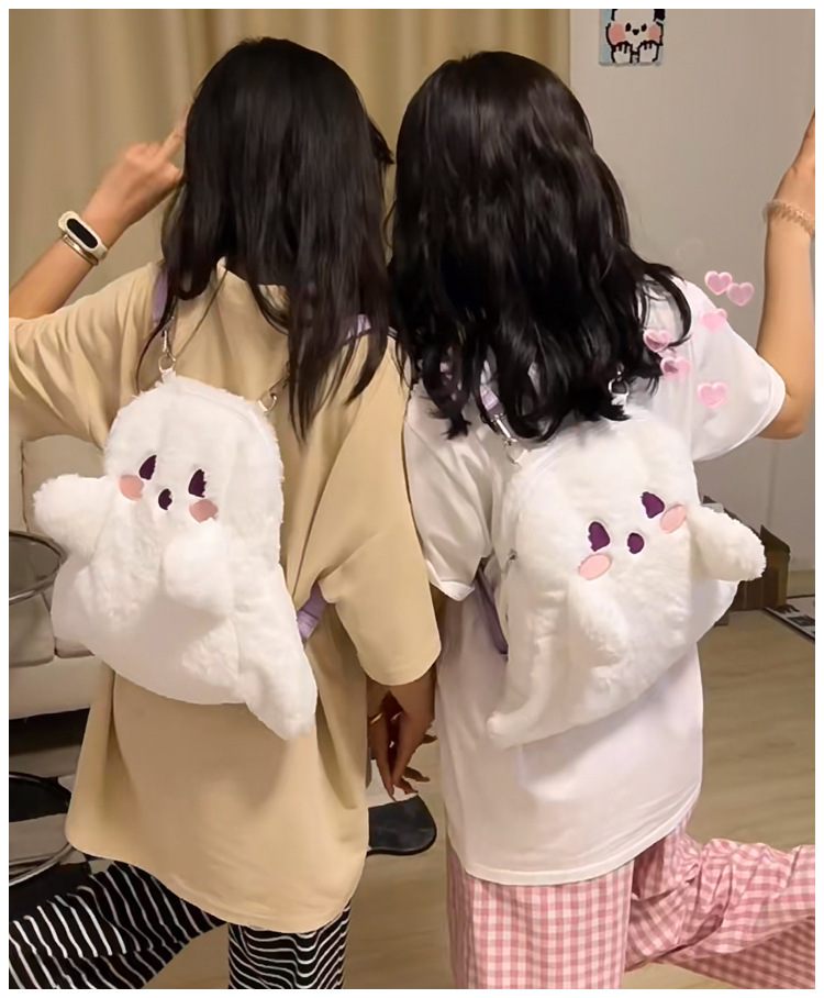 Two people wearing plush backpacks shaped like cartoon characters indoors.
