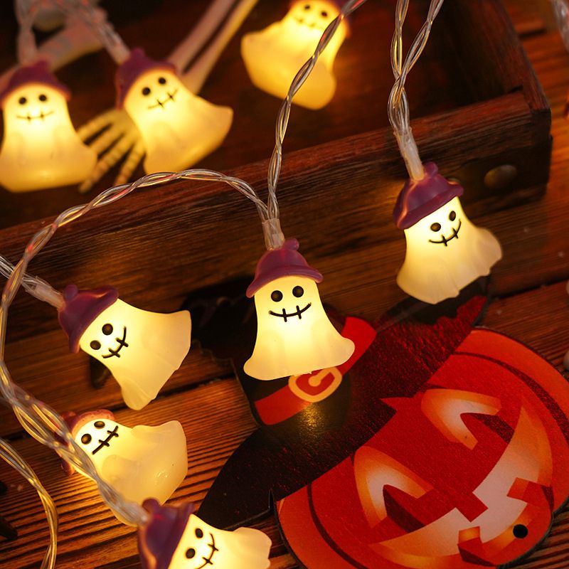 Halloween-themed string lights with ghost characters on a wooden surface with a pumpkin.