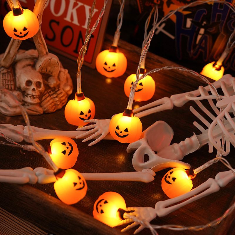 Halloween-themed string lights with pumpkin and skeleton design on a wooden surface.
