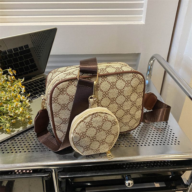 Patterned handbag and small pouch on a metallic surface with a laptop in the background.