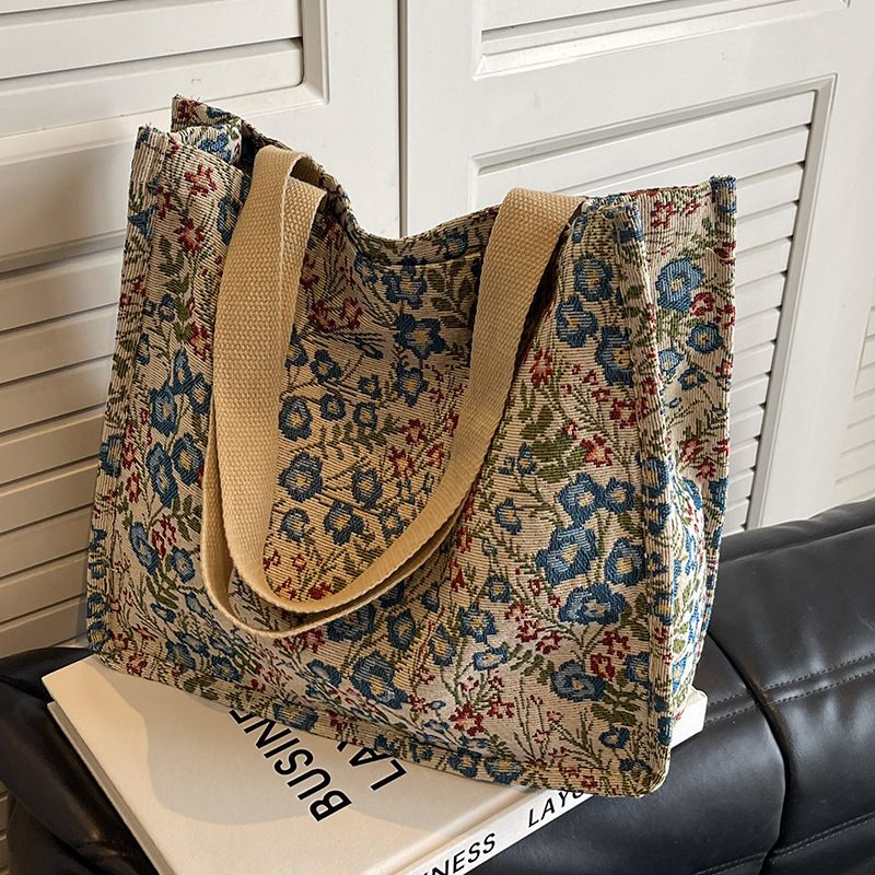 Floral patterned tote bag with beige handles on a surface.