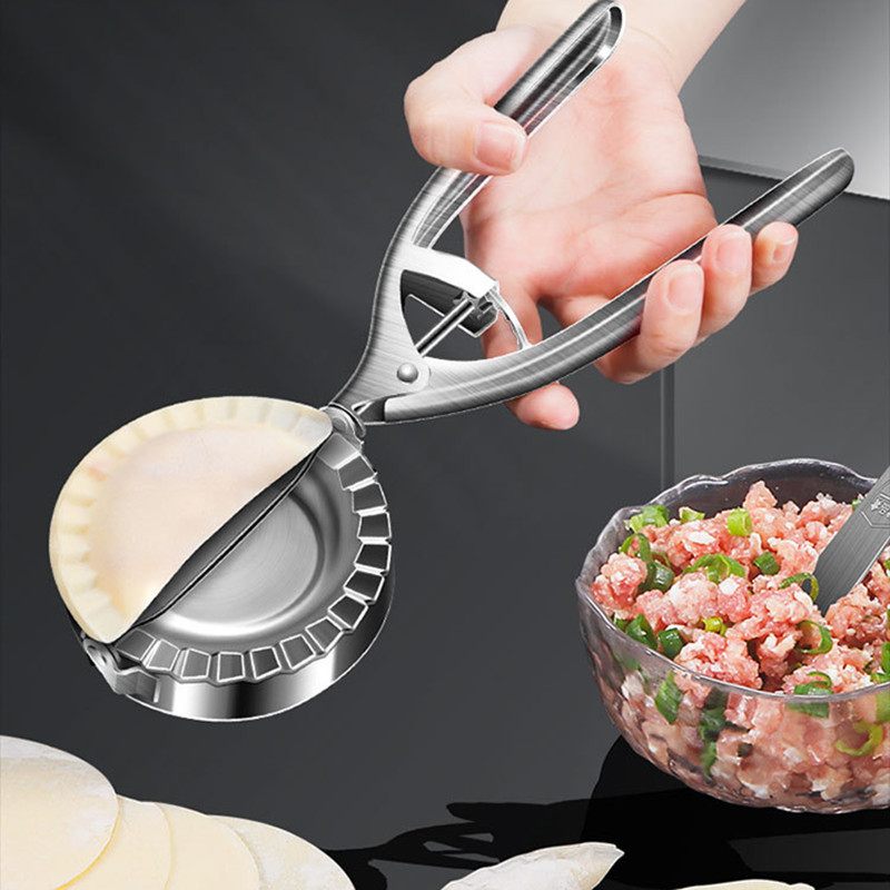 Hand using a metal dough press to form a round piece of dough, with a bowl of ground meat and vegetables in the background.