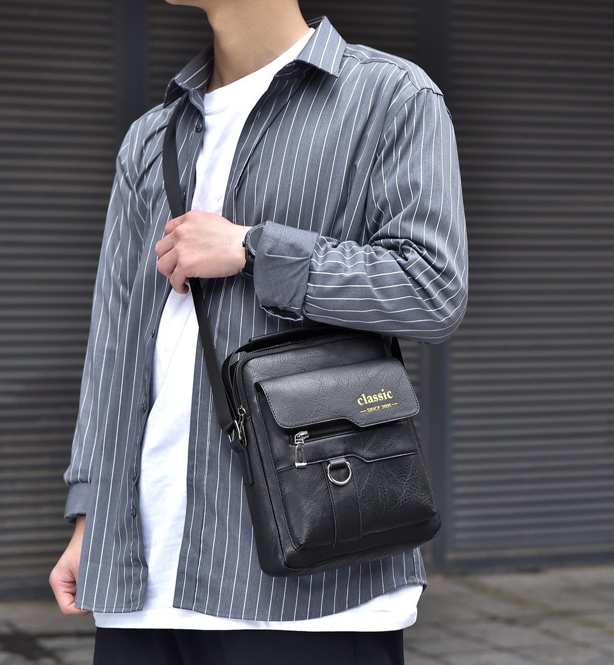 Person wearing a black leather bag with 'classic' branding against a gray background