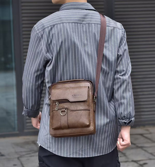 Person wearing a brown leather crossbody bag with a striped shirt outdoors.