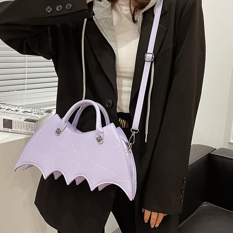 Person holding a unique bat-shaped handbag in an indoor setting