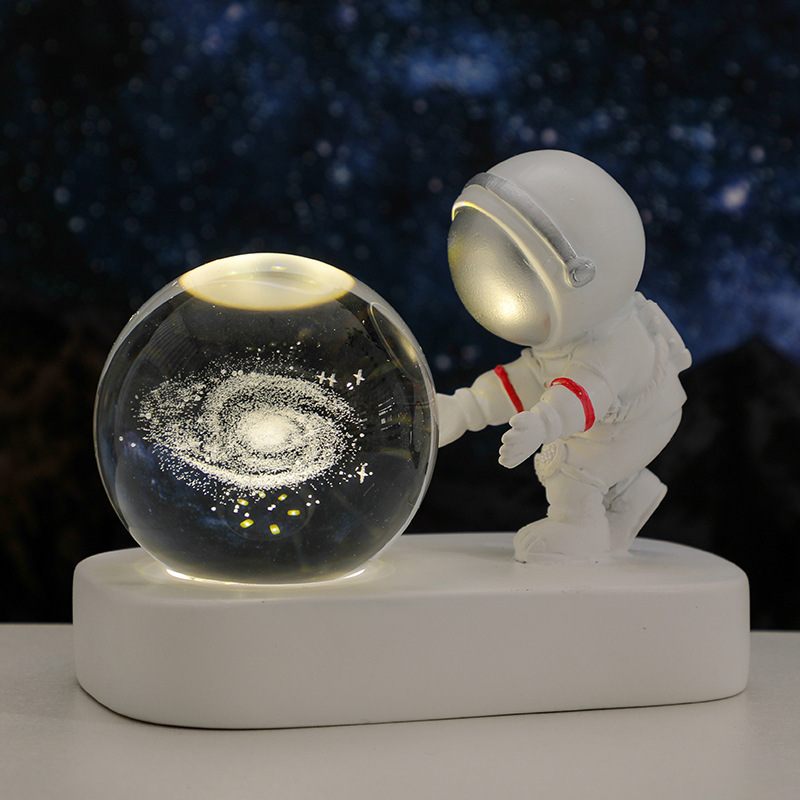 Spaceman figurine interacting with a galaxy model on a dark background