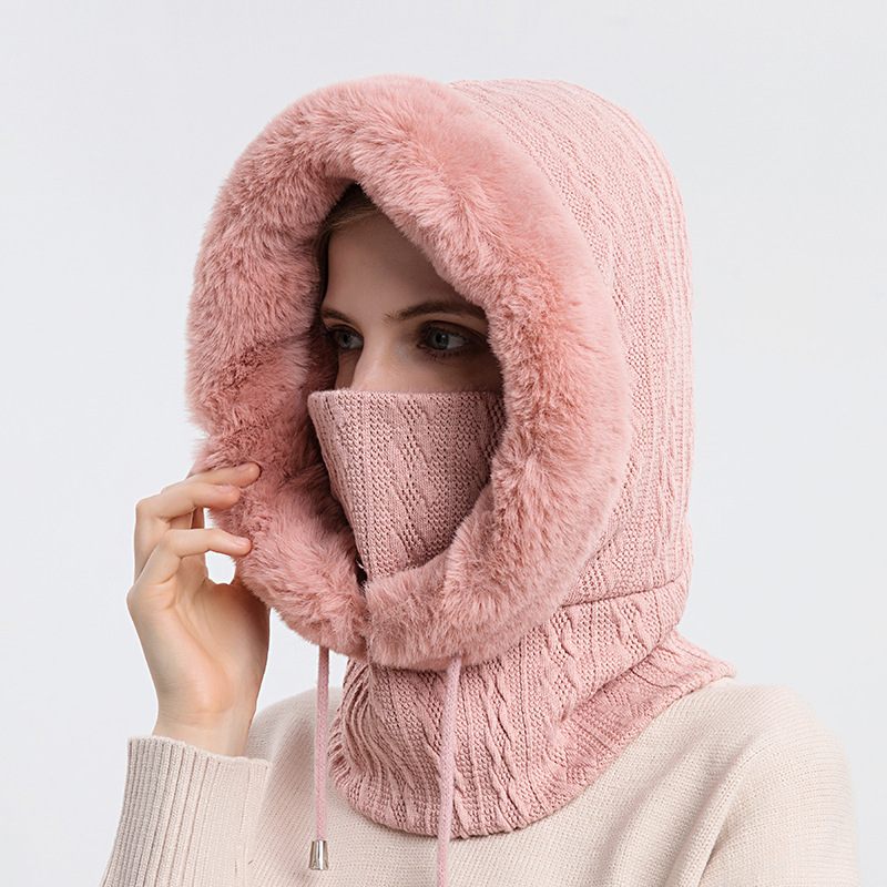 Person wearing a pink knitted hood and face mask on a light gray background