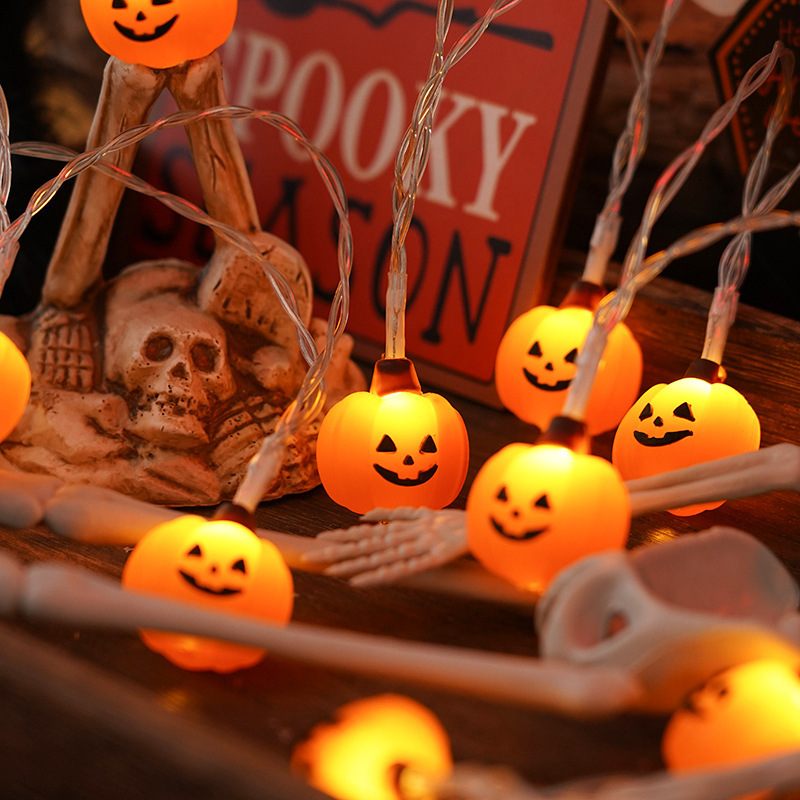 Halloween-themed string lights with pumpkin faces on a decorative setup.