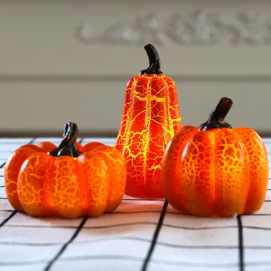 Three decorative pumpkins with a cracked texture on a white surface.