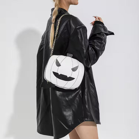 Person wearing a black leather jacket with a pumpkin face bag on a white background