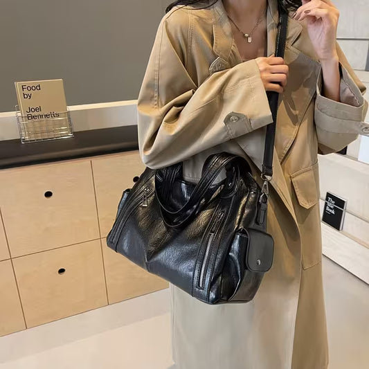 Person holding a black leather handbag in an indoor setting