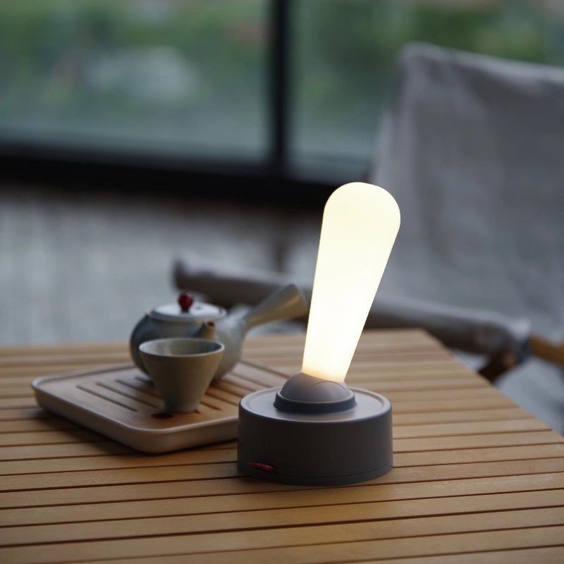 Modern table lamp on a wooden surface with a blurred outdoor background