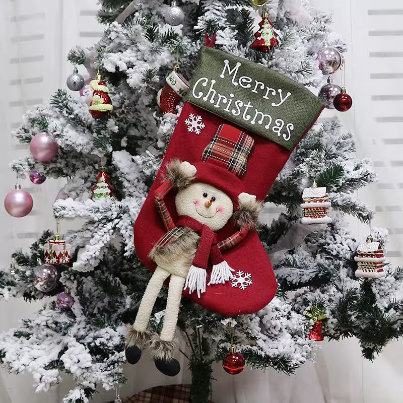 Red Christmas stocking with a snowman design hanging on a decorated tree.