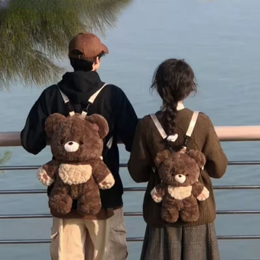 Two people wearing teddy bear backpacks by a body of water.