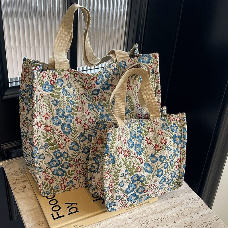 Two floral-patterned tote bags on a wooden surface with a dark background
