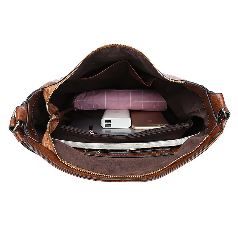 Brown leather bag with compartments containing a purple notebook, white power bank, and other items on a white background.