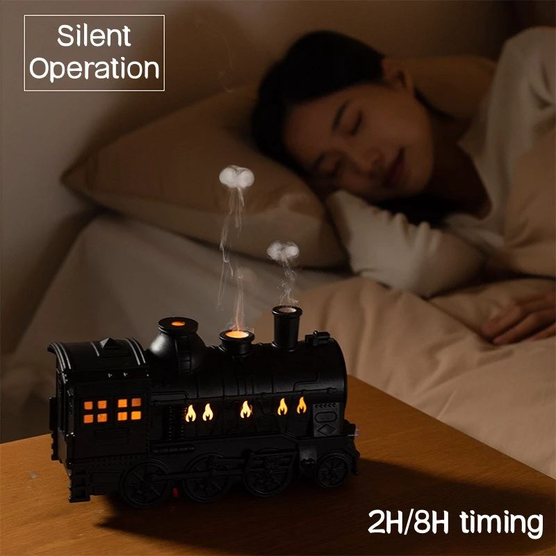Steam train night light on a bedside table with a person sleeping in the background.