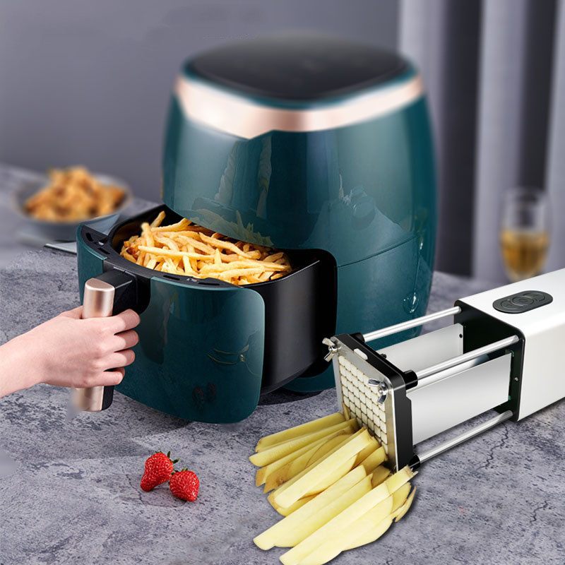 Green air fryer with a basket of fries on a gray surface, next to a manual potato peeler.