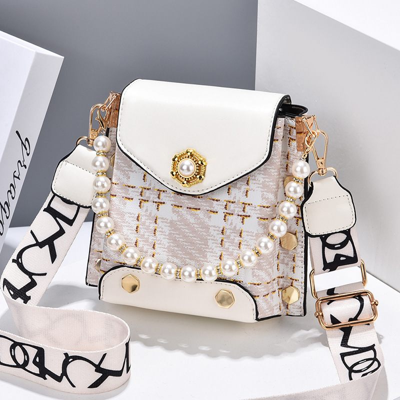 White handbag with pearl embellishments and a decorative strap on a light gray background