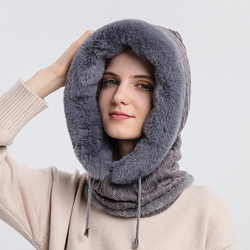 Person wearing a gray fur-lined hooded scarf against a white background