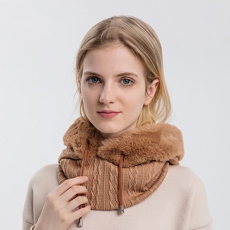 Woman wearing a brown knitted cowl with fur trim against a white background