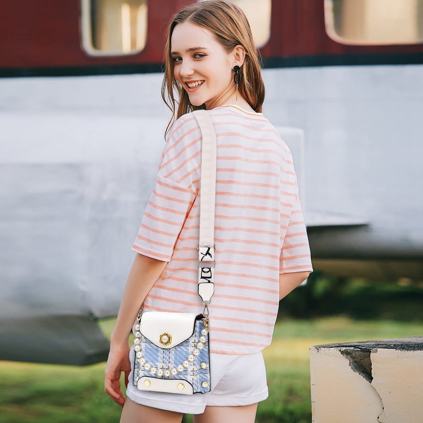 Woman in a striped shirt with a decorative handbag standing in front of a vintage-style vehicle.