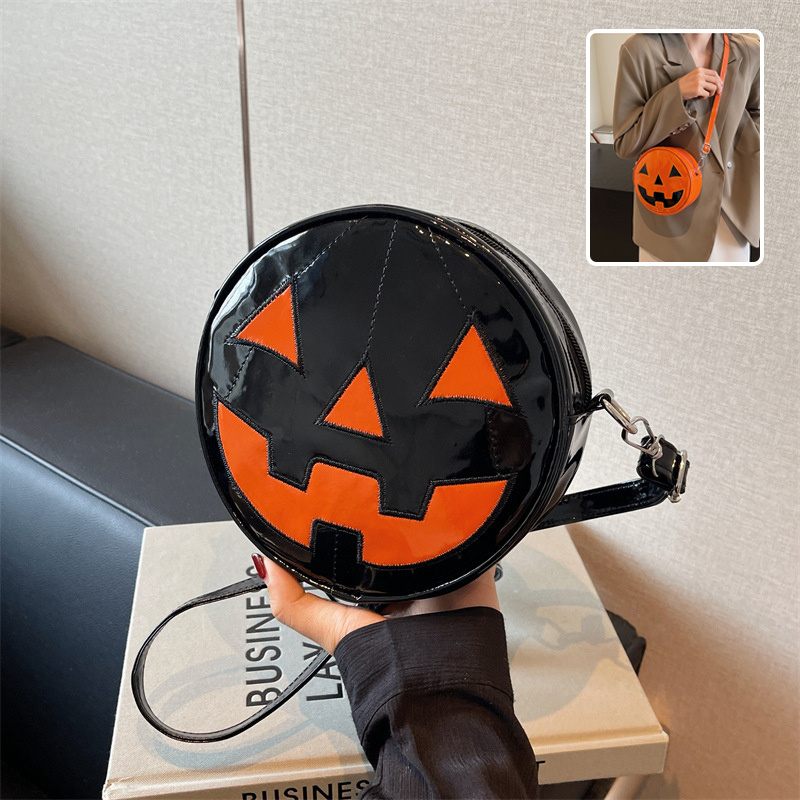 Round black and orange Halloween bag with jack-o'-lantern design held by a person.